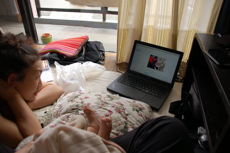パソコンを寝転がりながら眺める女性